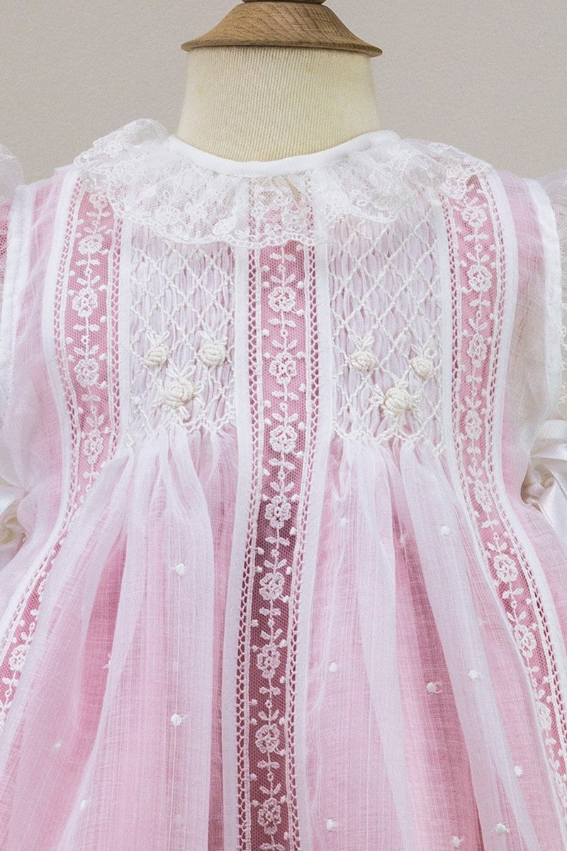 Pink dress with white lace details on a mannequin against a neutral background