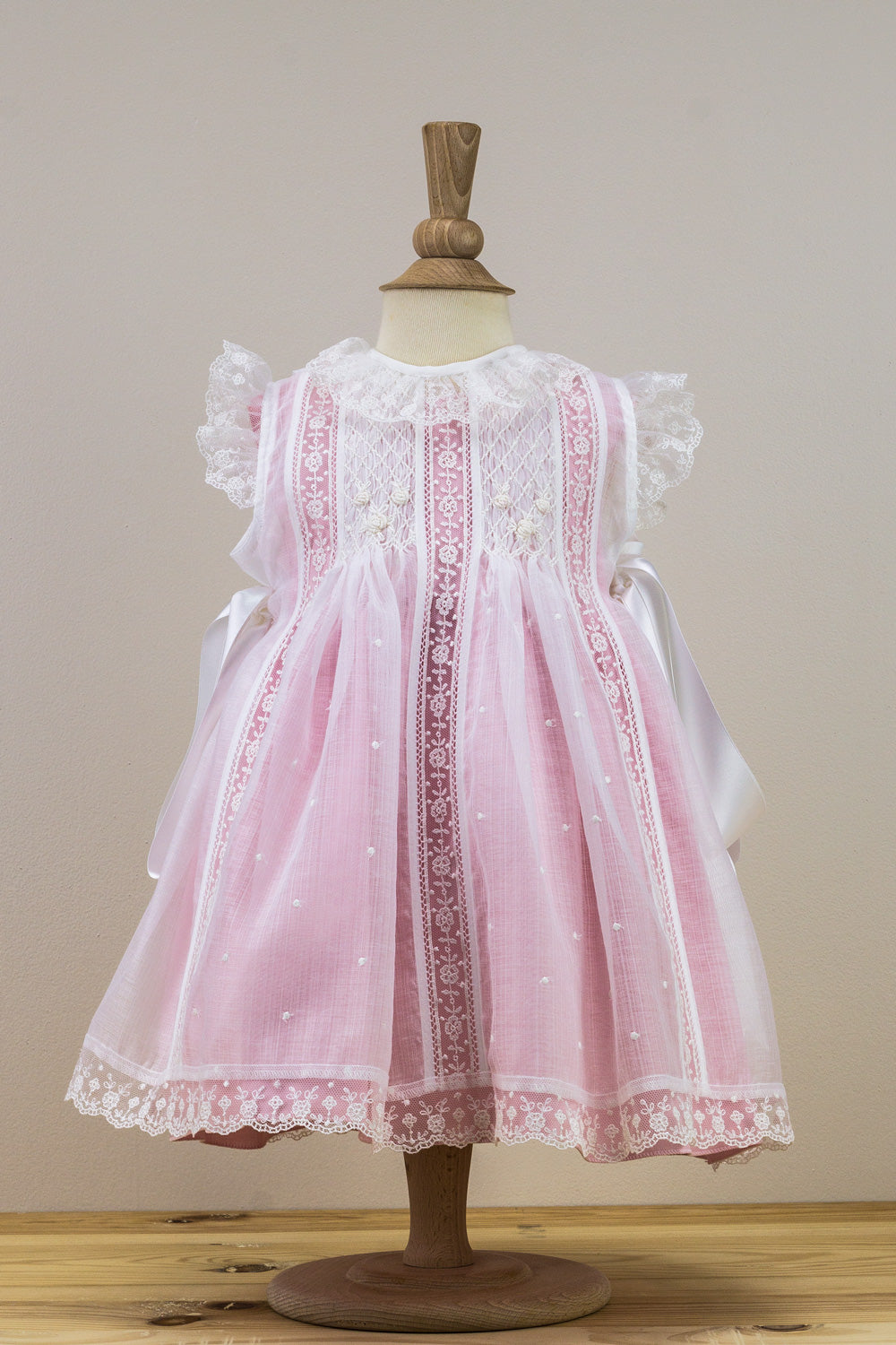 Pink lace dress on a mannequin against a plain background